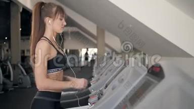 一个女人在跑步机上跑步的特写。 白色运动鞋运动。 女运动员训练快运动员